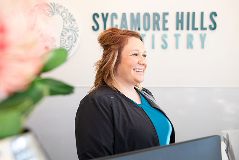 staff member smiling at the front desk of the dental center waiting to help incoming patients