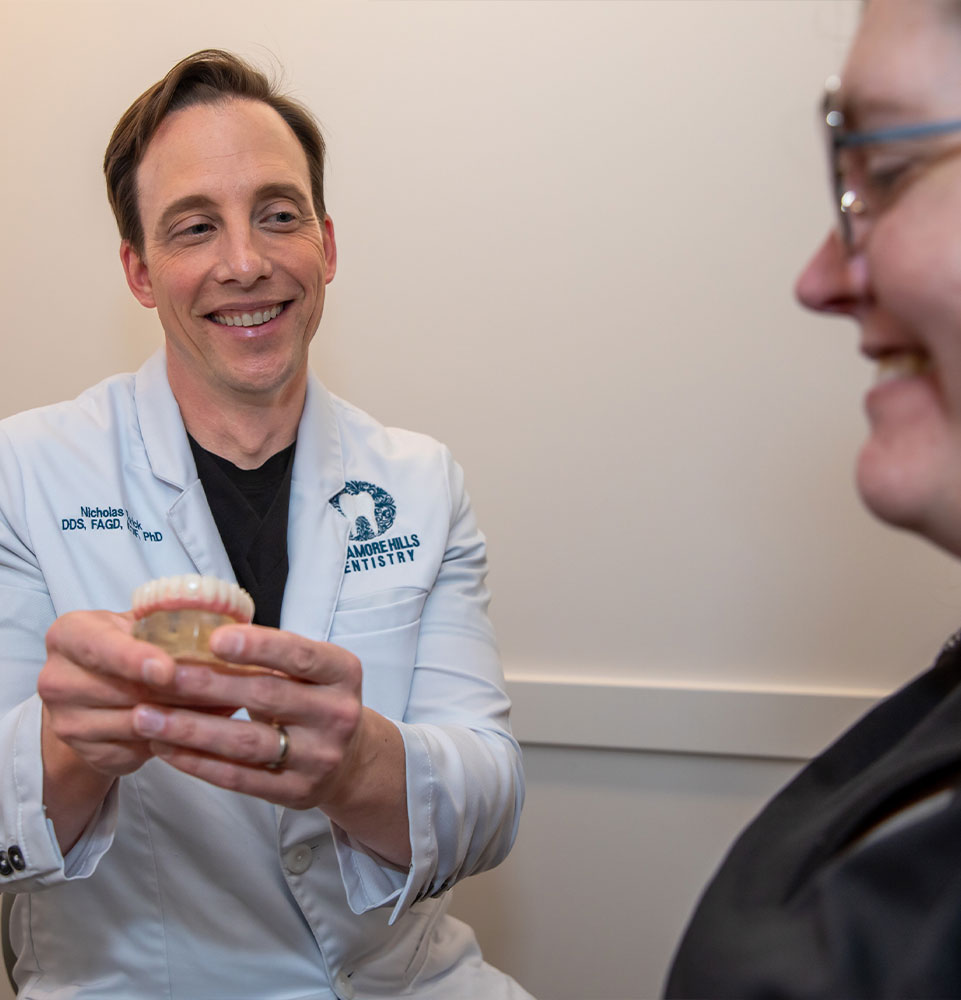 dentist holding full arch implant showing patient