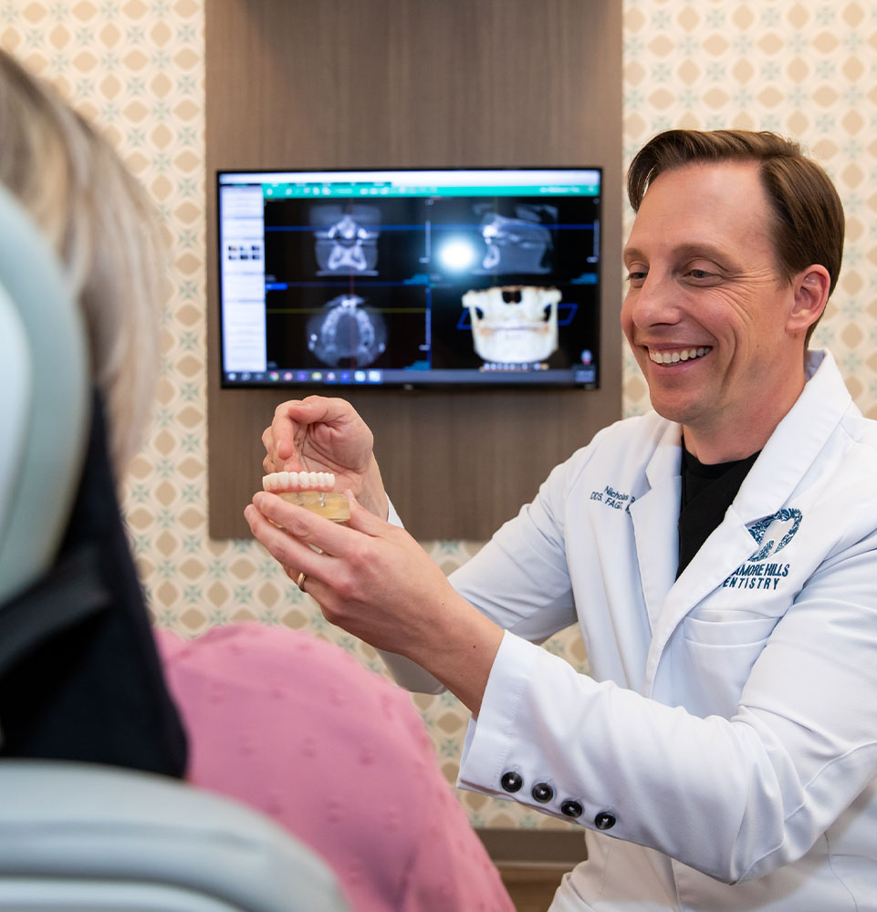 dentist showing patient a model of a Full arch dental implant