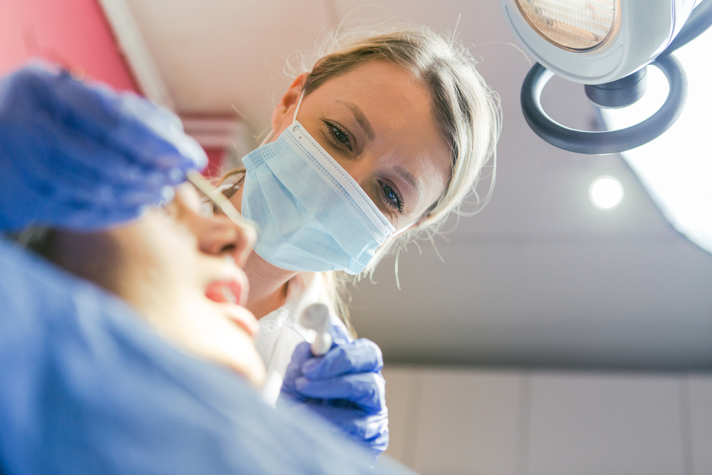 Photo of a diverse group of dental professionals, including a surgeon and a prosthodontist, collaborating on a dental implant case using 3D imaging technology. The scene is in a modern dental office. No text on the image.